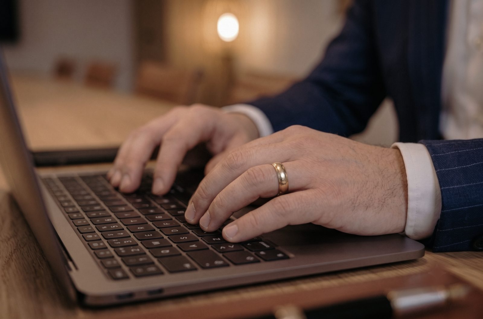 Person in a suit typing on a laptop